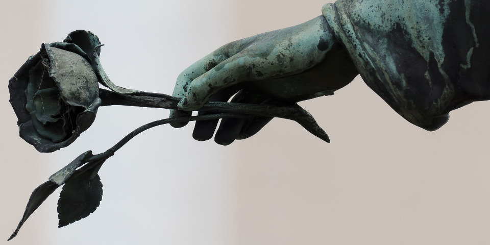Close up of a cemetery statue hand holding a rose